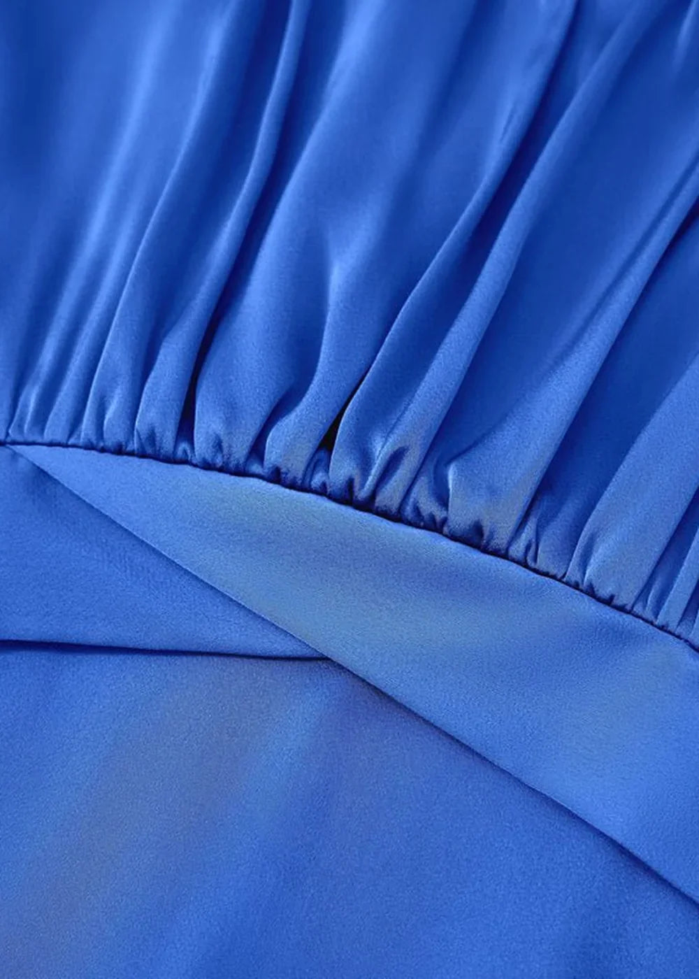 Close-up of royal blue polyester fabric with ruched detailing and a smooth overlay.