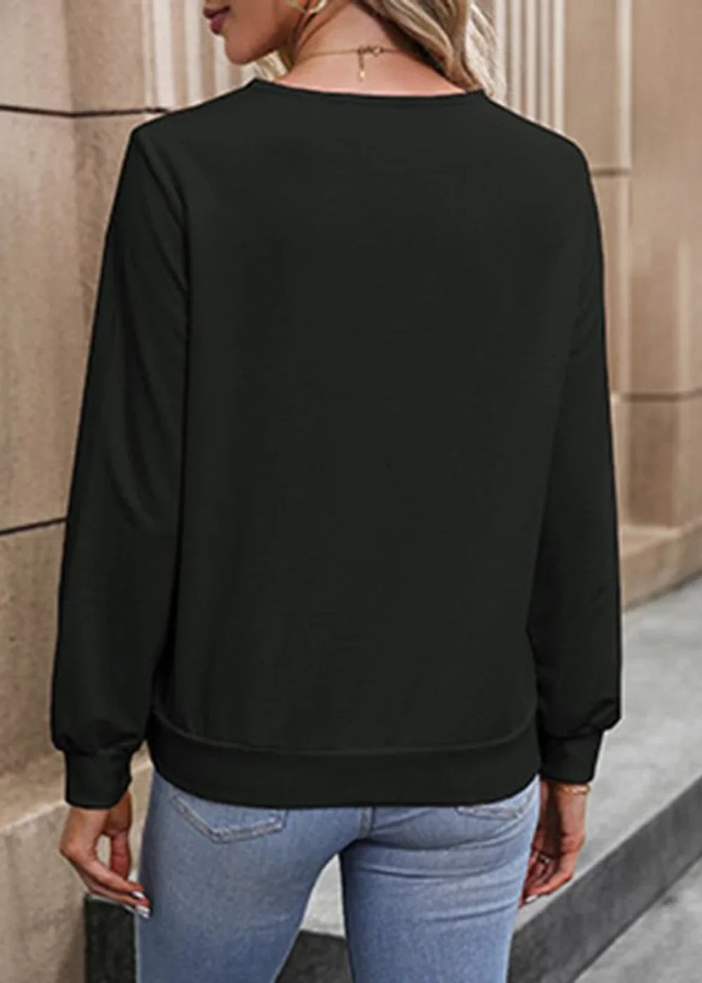 Black long-sleeved sweatshirt with crew neck and ribbed cuffs and hem, worn by a model with light wash jeans.