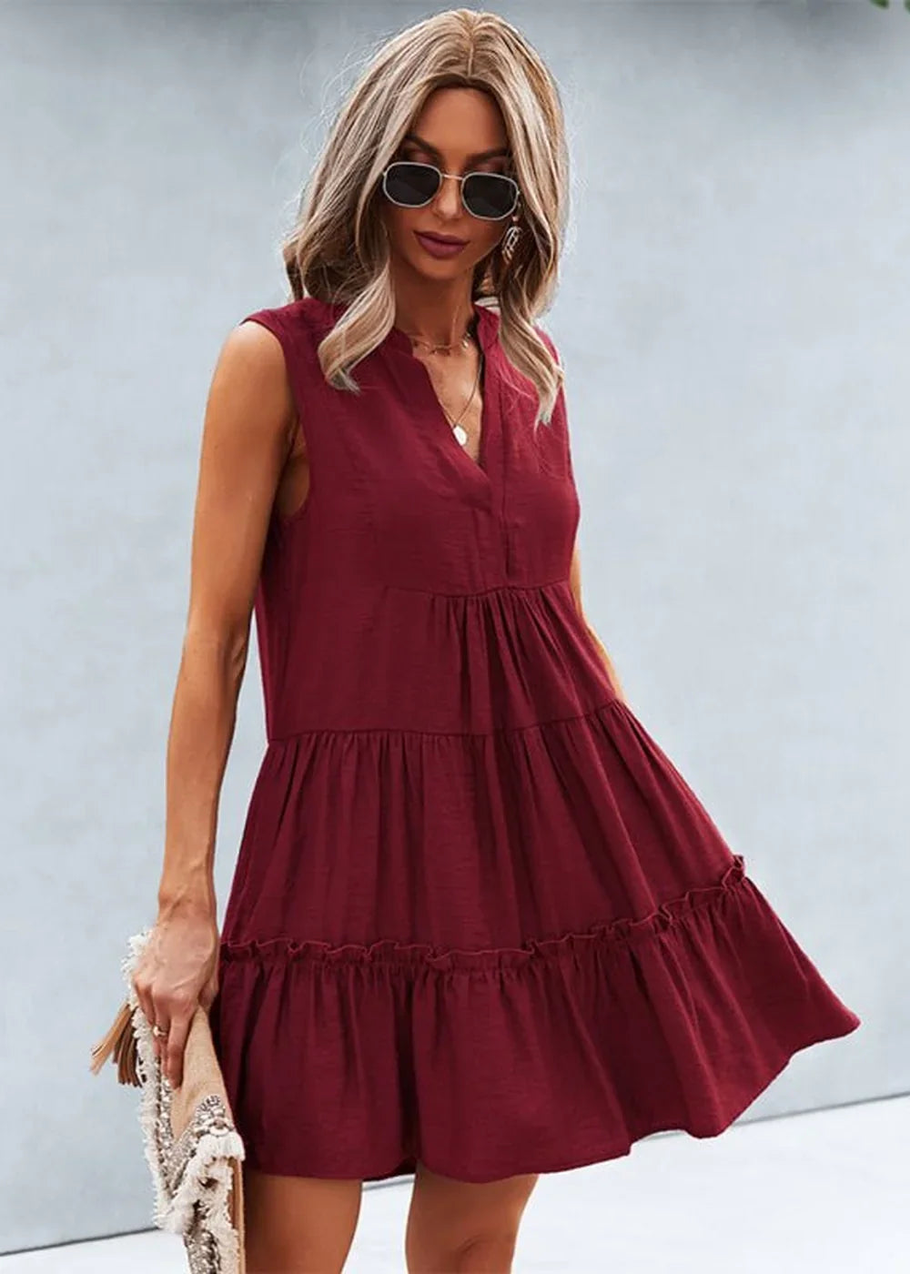 Burgundy tiered sleeveless V-neck dress with a ruffled hem, worn by a model holding a fringed clutch.