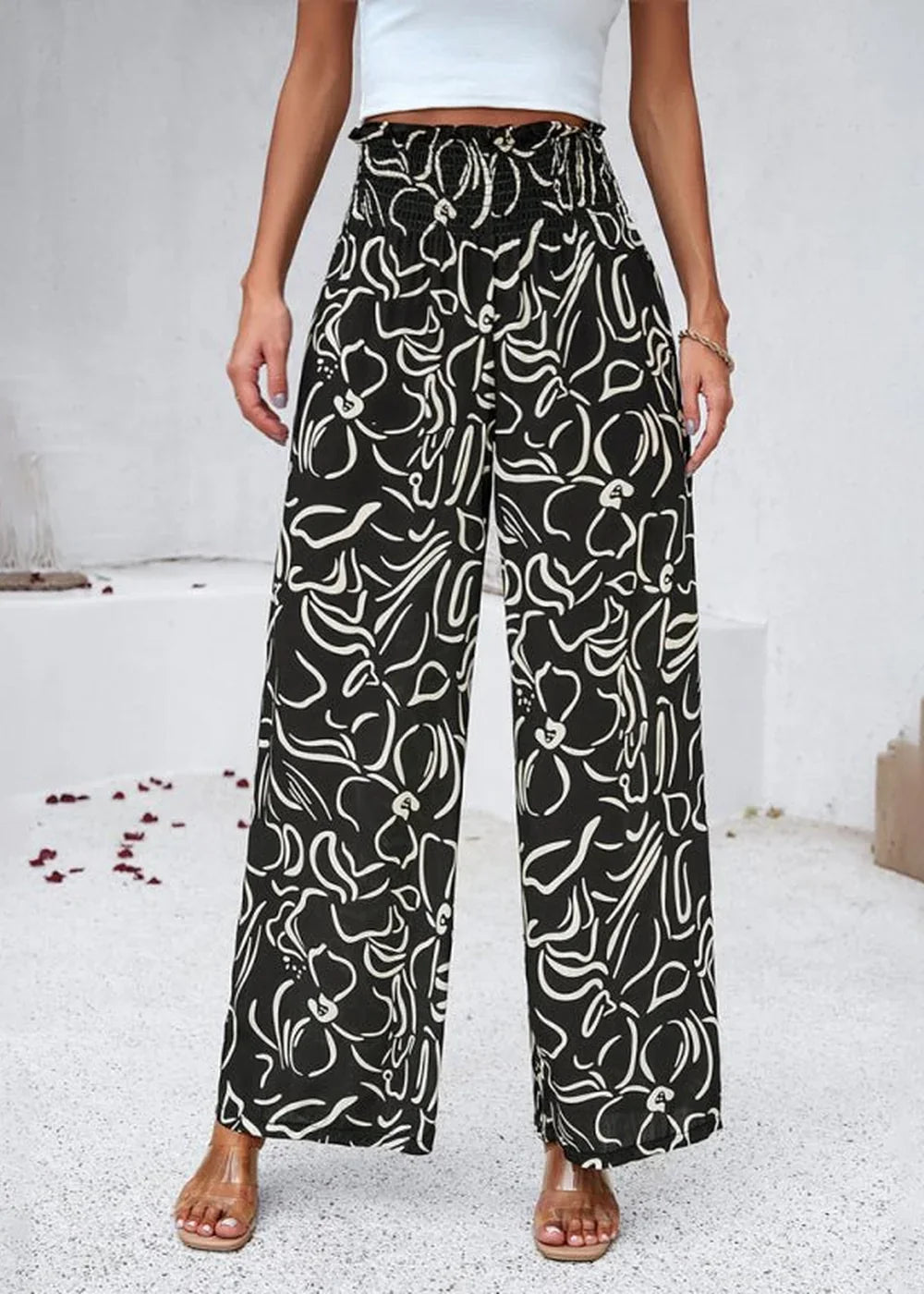 Black wide-leg pants with a white abstract floral print and smocked high waist.