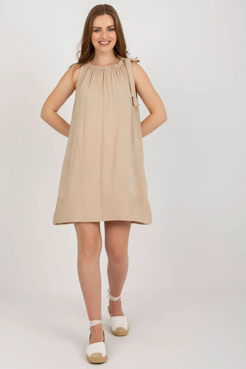 Loose-fit, sleeveless beige viscose dress with tie shoulder details on model.