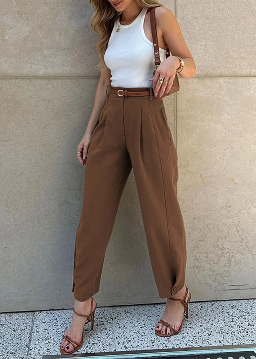 Brown pleated trousers with a brown belt and brown strappy heels on a model.