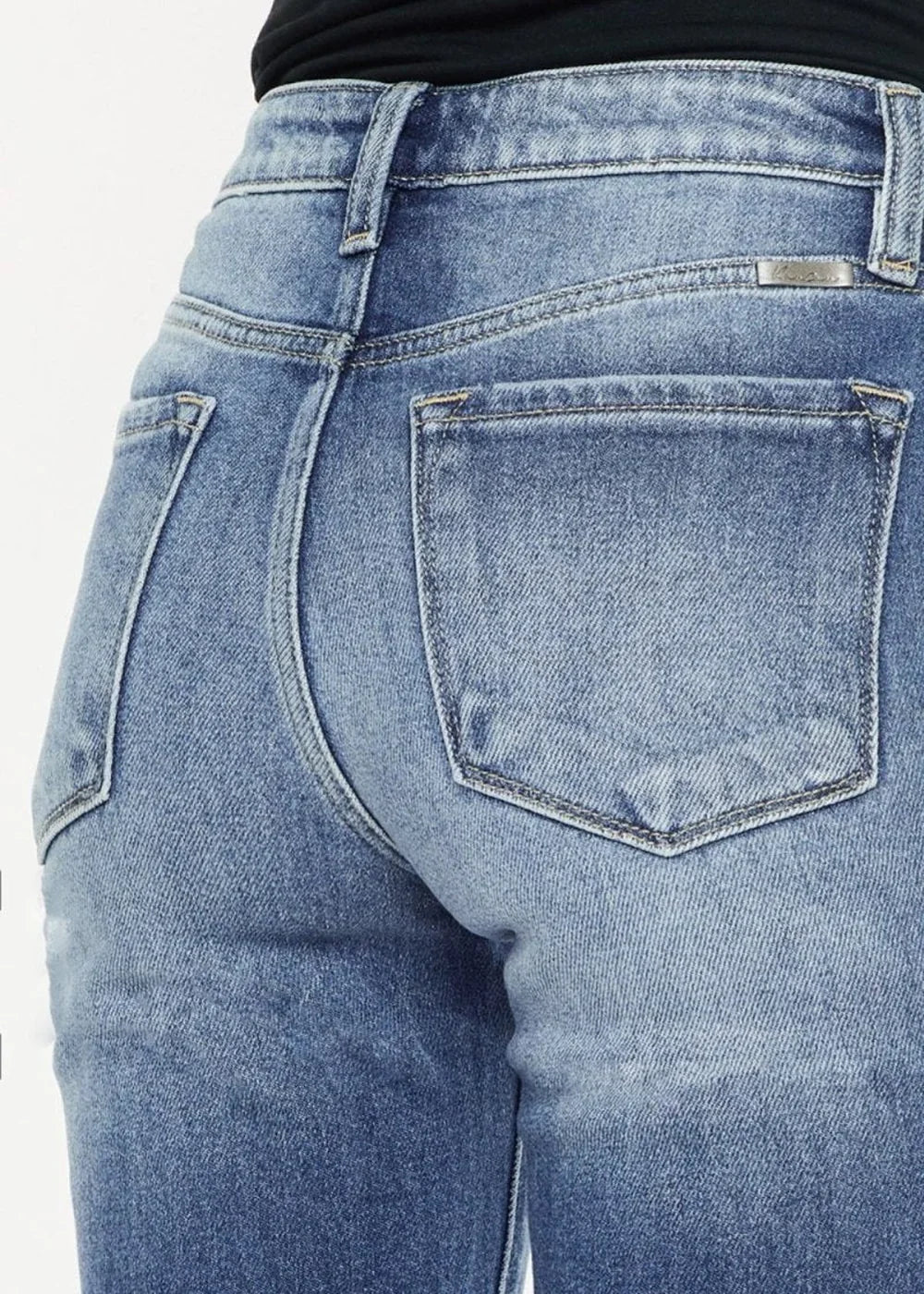 Close-up of light blue distressed denim jeans, showing back pockets and seams.