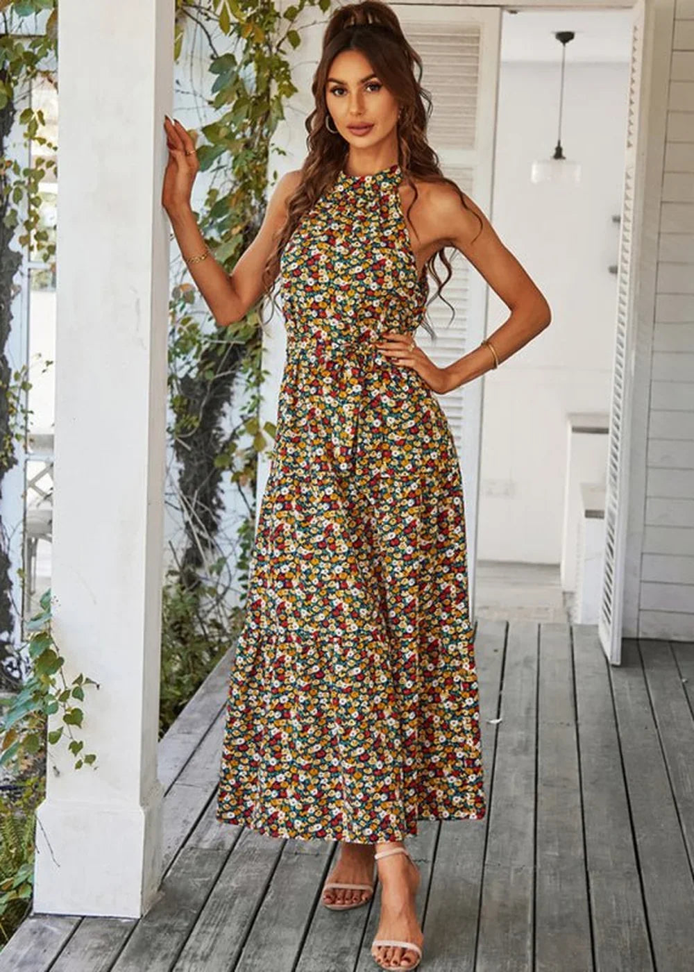 Woman in a sleeveless floral print maxi dress with a halter neck and sandals.