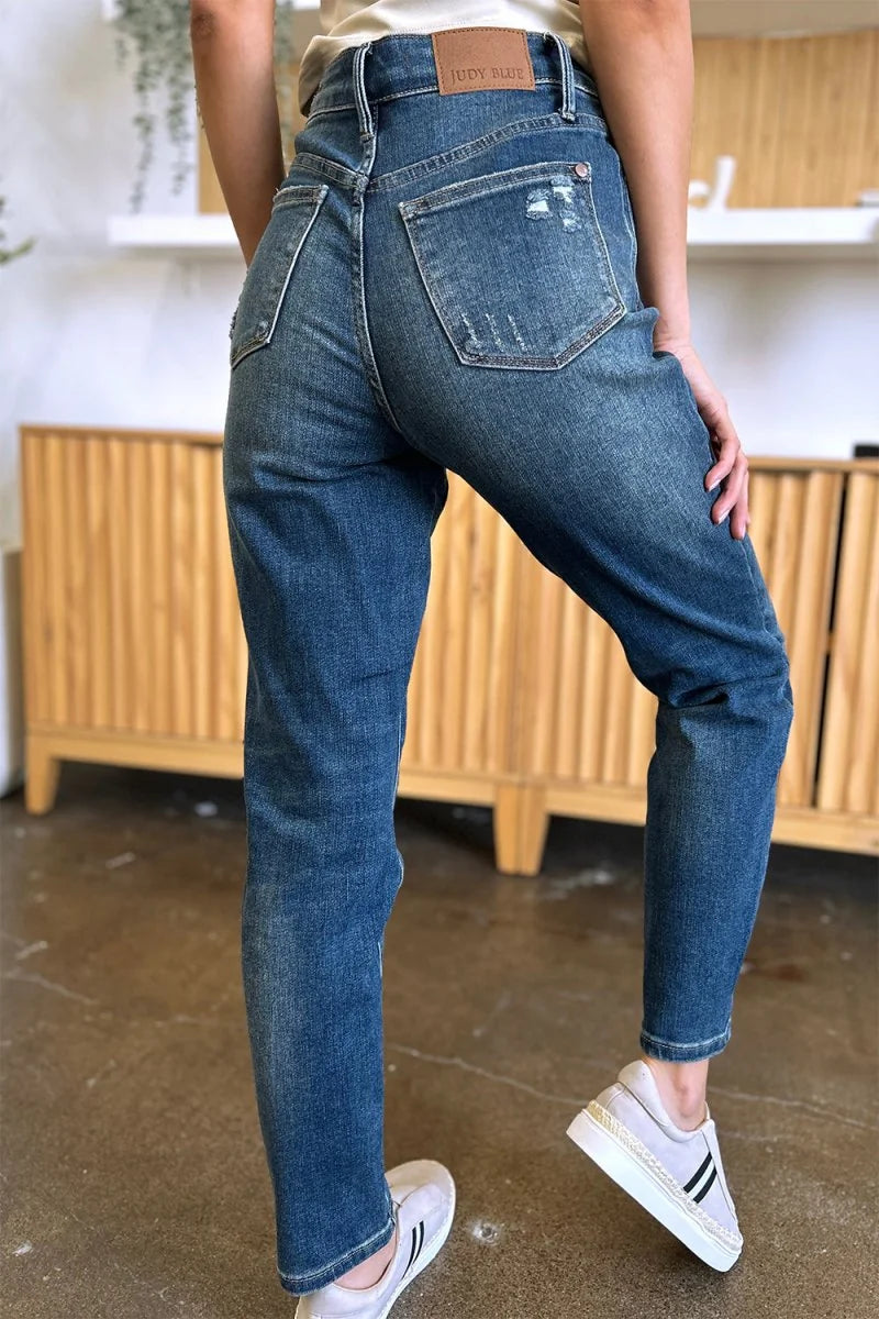 Distressed, medium-wash denim jeans with a straight leg fit, shown from the back.
