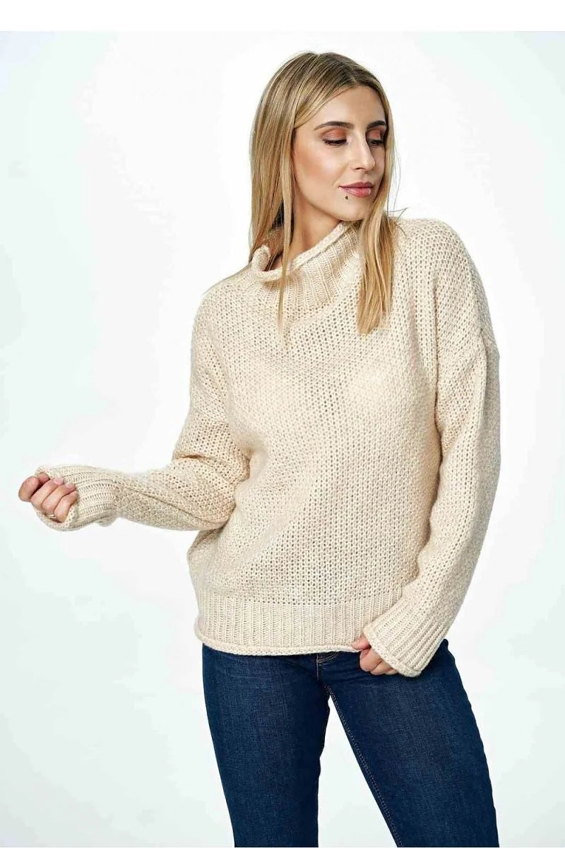 Beige knit sweater with a cowl neck and ribbed cuffs and hem on a model.
