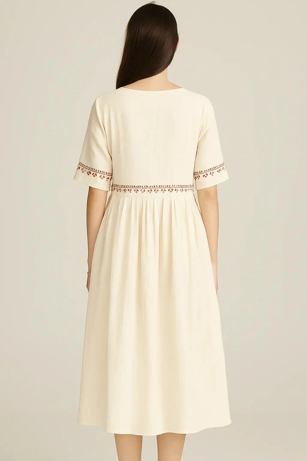 Cream midi dress with embroidered trim on sleeves and waist, gathered skirt.