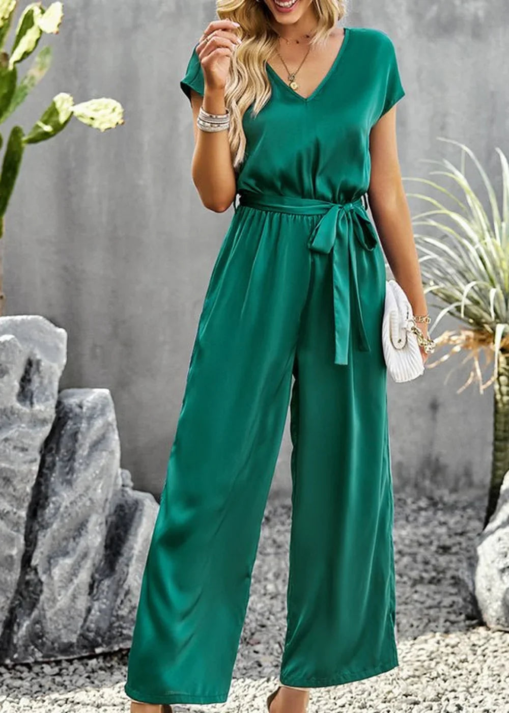 Emerald green satin jumpsuit with V-neck, short sleeves, and tie belt, on a model.