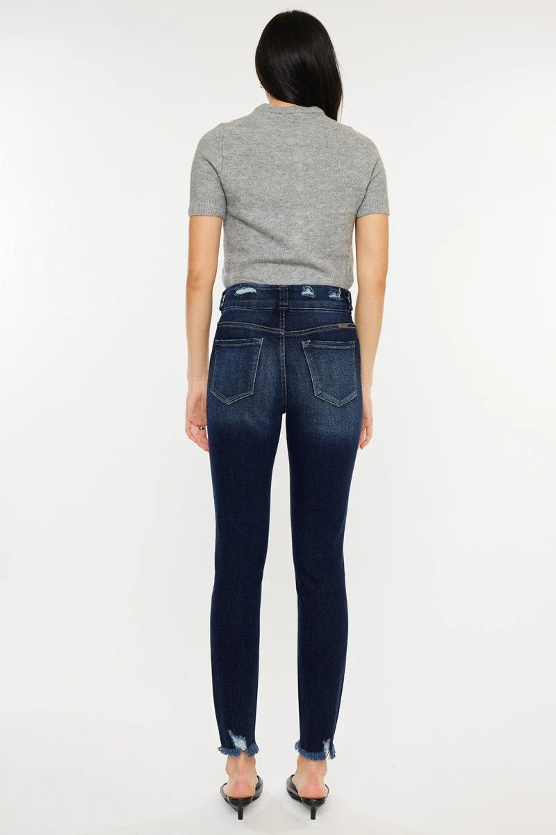 Dark wash denim jeans with frayed hem and a distressed waistband, shown on a model from the back.