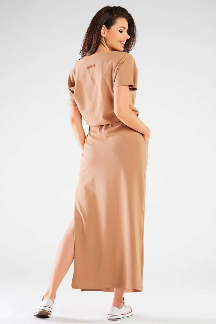Woman in a tan cotton-blend maxi dress with a side slit and white sneakers.