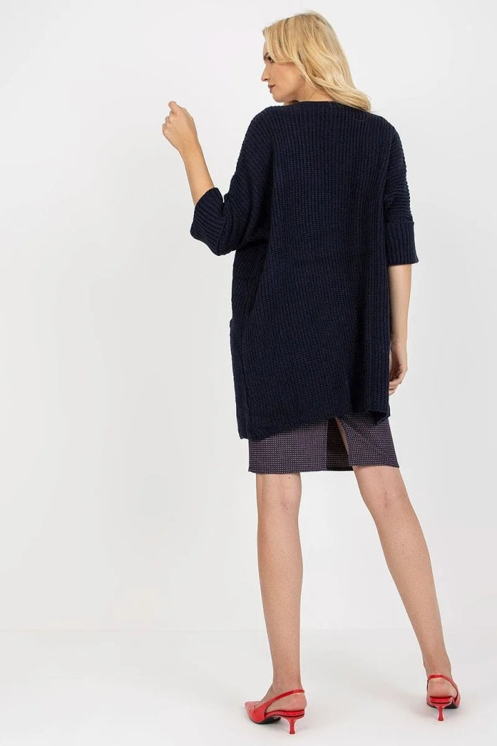 Navy blue ribbed knit cardigan with short sleeves worn over a dark plaid skirt.