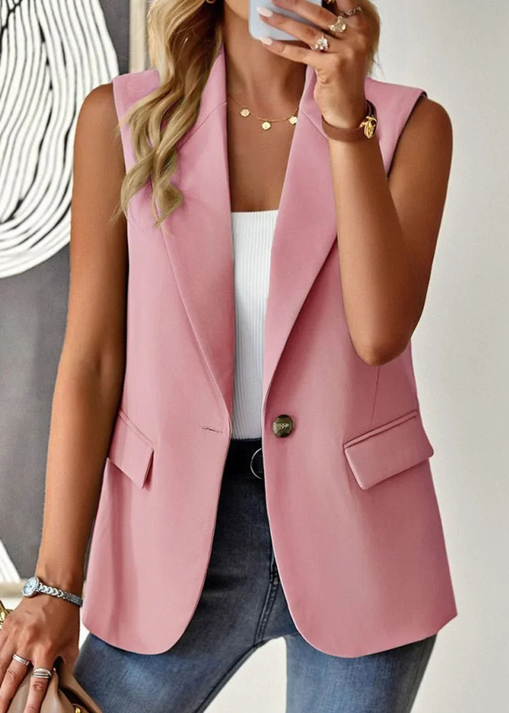 Pink sleeveless blazer with a single button closure and flap pockets, worn by a model.