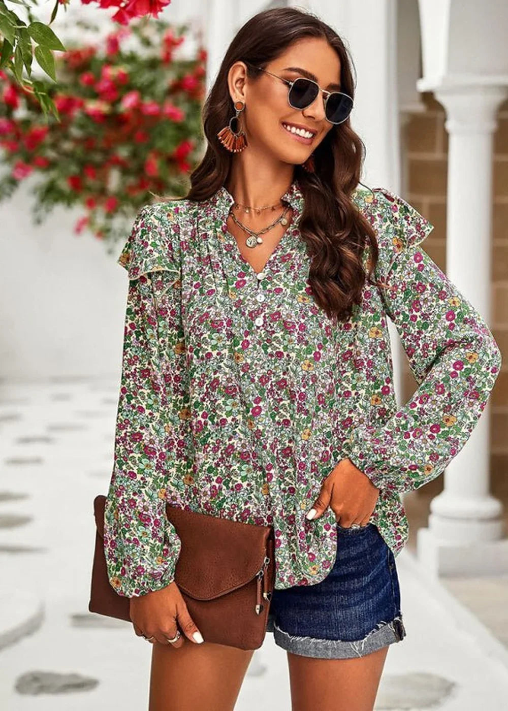 Woman in a floral print blouse with ruffled sleeves and denim shorts, holding a brown clutch.