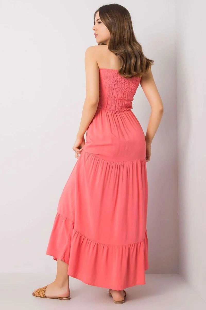 Coral pink strapless maxi dress with smocked bodice and tiered ruffled skirt, worn by a model.