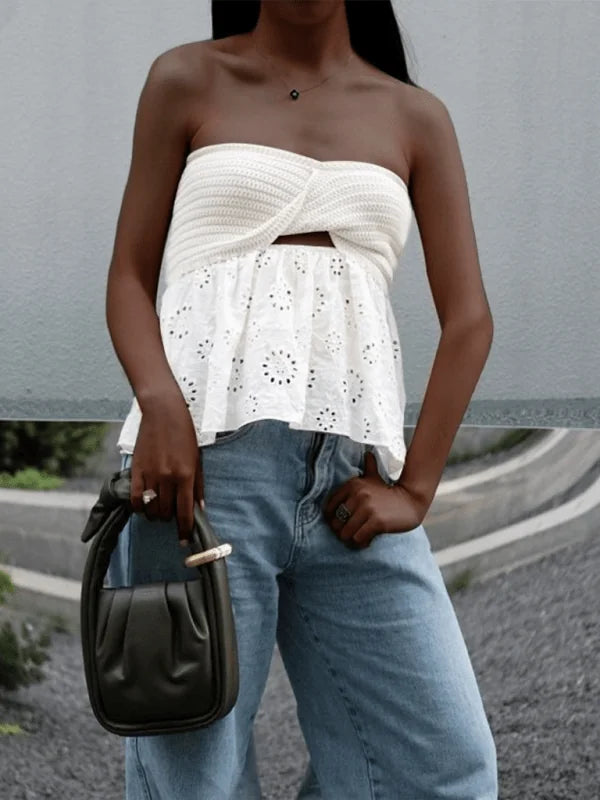 White crochet strapless top with eyelet trim and cutout detail, paired with light wash denim jeans.