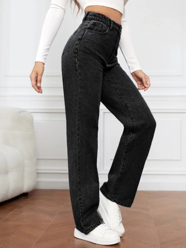 Black denim jeans with a regular fit, showing texture and detail on a model.