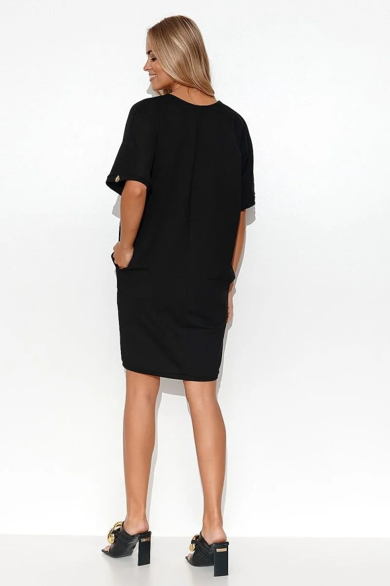 Black cotton blend t-shirt dress with short sleeves, pockets, and gold chain detail on black heels.