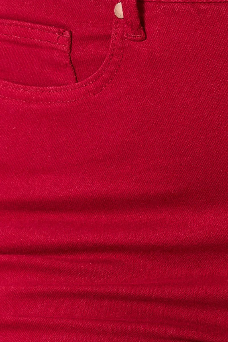 Close-up of red denim fabric with visible stitching detail on pocket.