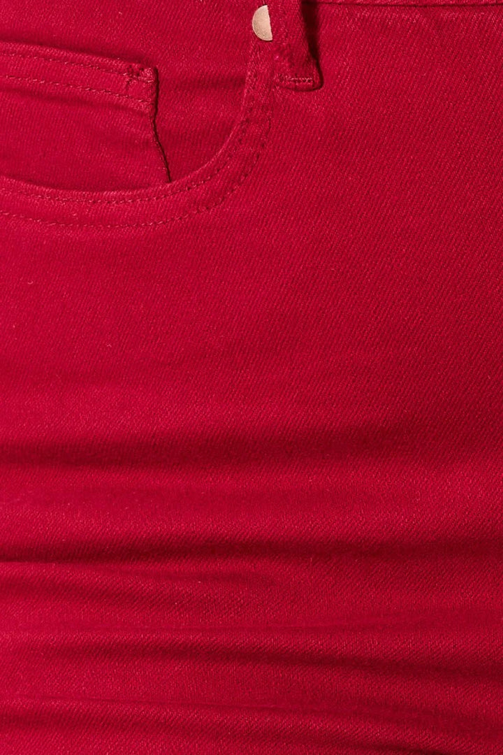 Close-up of red denim fabric with visible stitching detail on pocket.