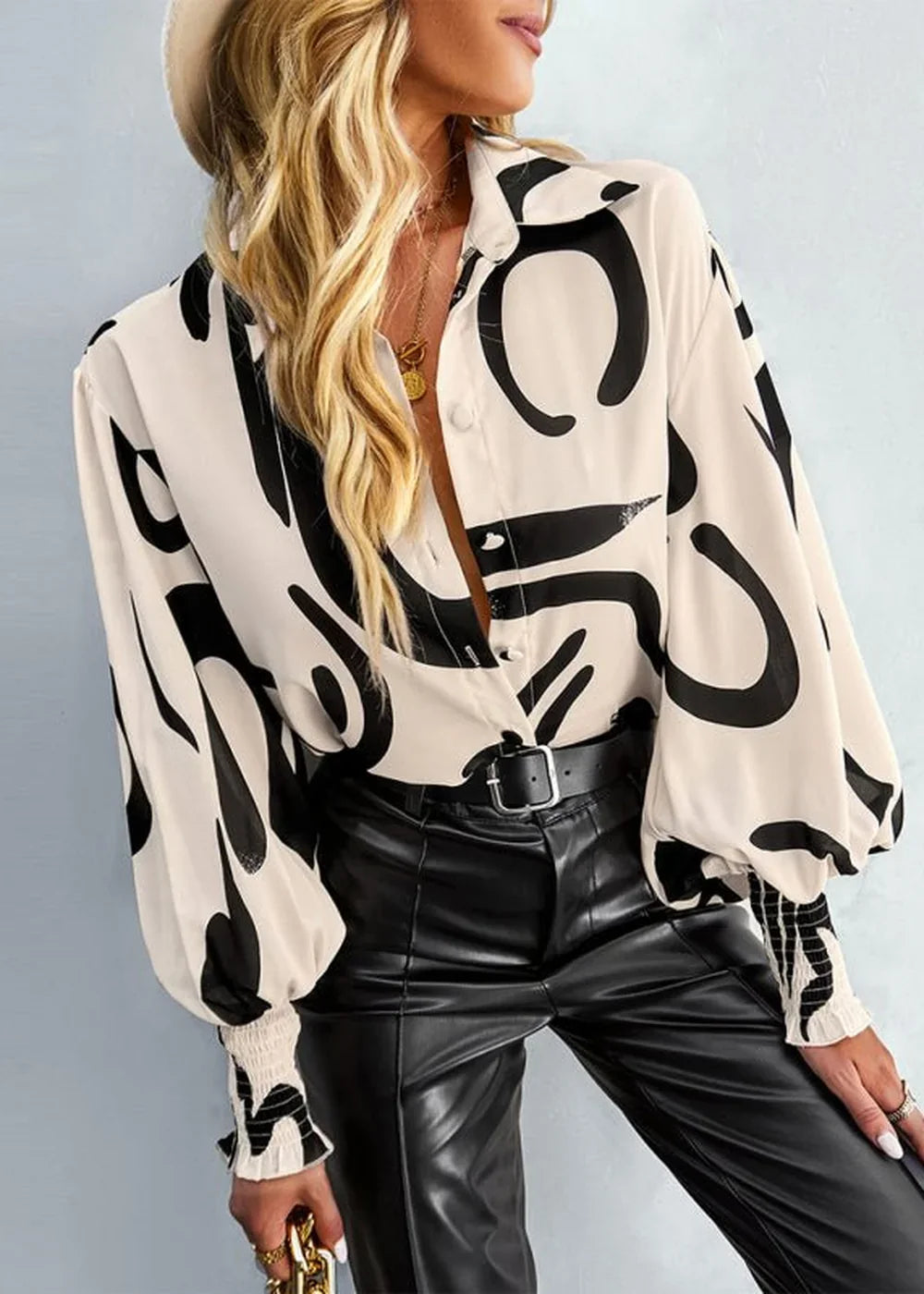 Cream and black abstract print long-sleeve blouse with a button-down front and elastic cuffs.