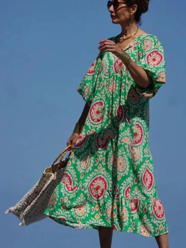 Green tiered maxi dress with a vibrant geometric pattern, on a model against a blue sky.