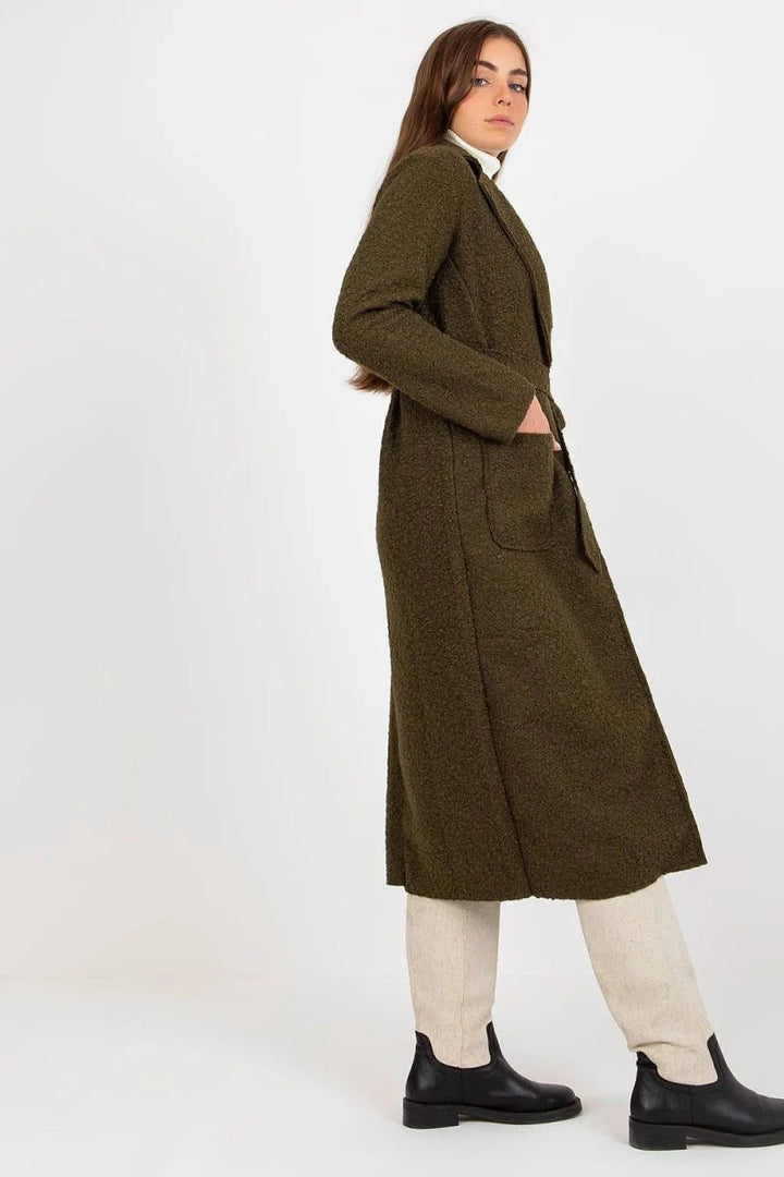 Textured olive green coat with belt and cream pants on model