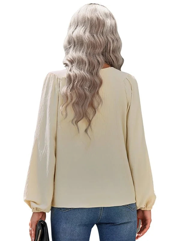 Back view of a cream-colored, long-sleeved blouse with a textured fabric.