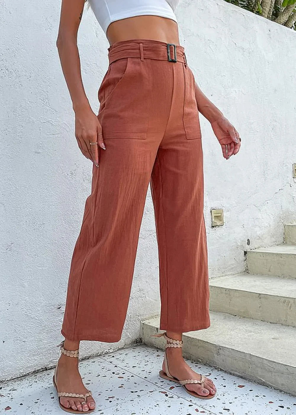 Rust colored linen blend cropped wide-leg pants with a belted waist and pocket details on a model.